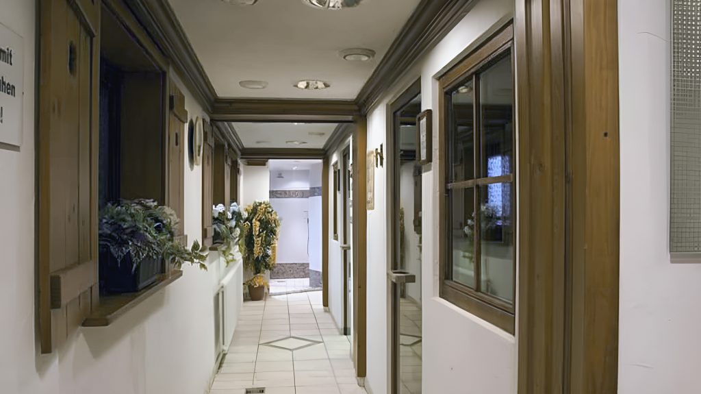 Heller Flur mit Holzelementen und Pflanzen, Fenster und Türen entlang der Wände.